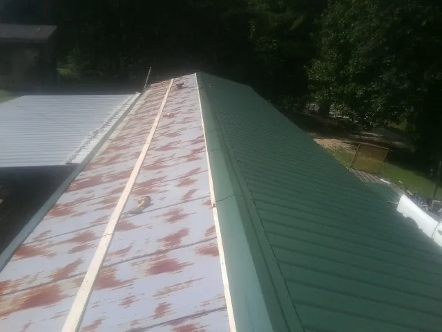 Old rusted panels beside newly installed green metal roofing — Wind Damage Roof Repair by Roofing Brothers in Morgan